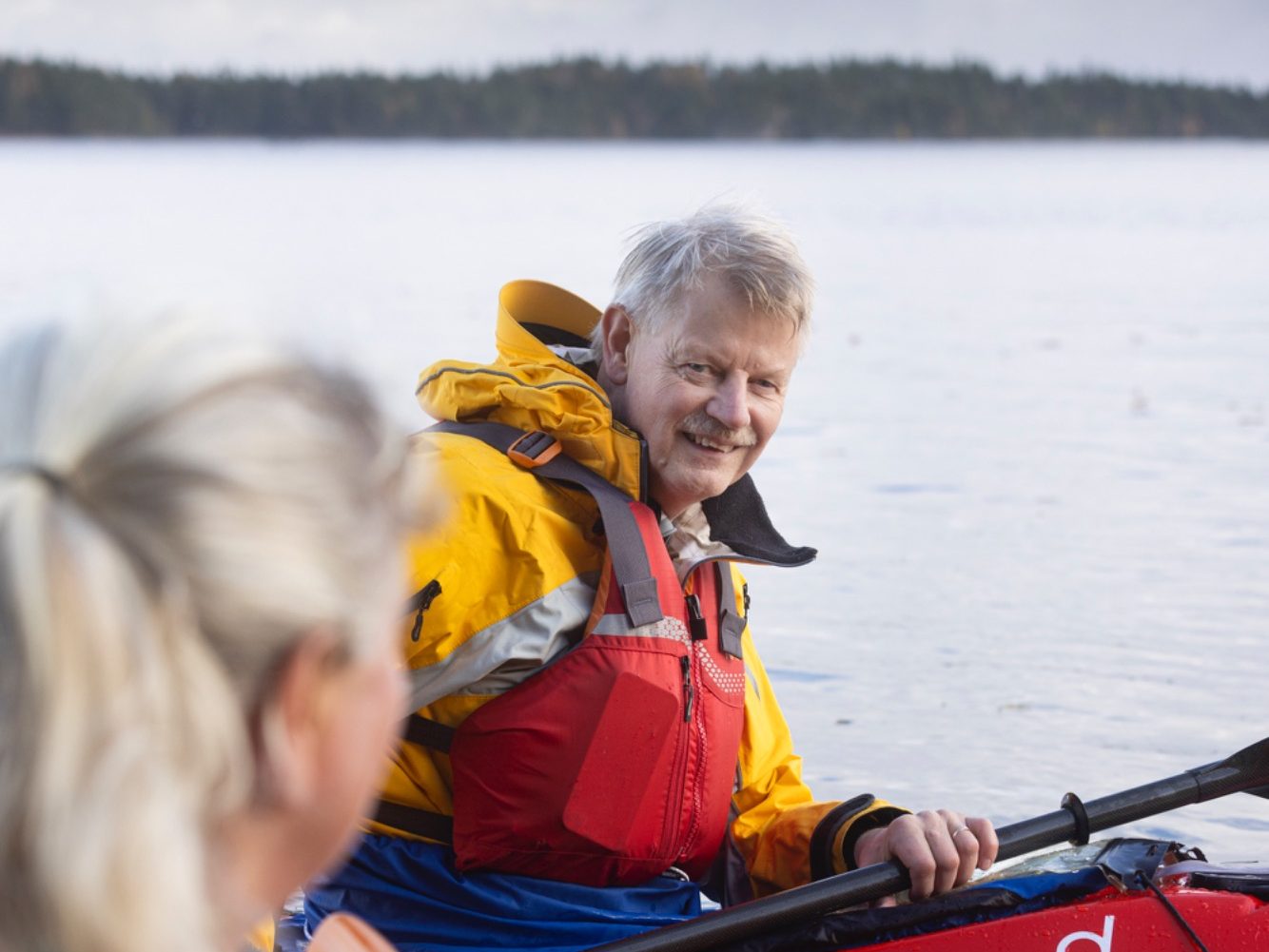 Paddelpasskurser på Vättern Två paddlare i kanot vid en sjö, en med grått hår och orange flytväst.